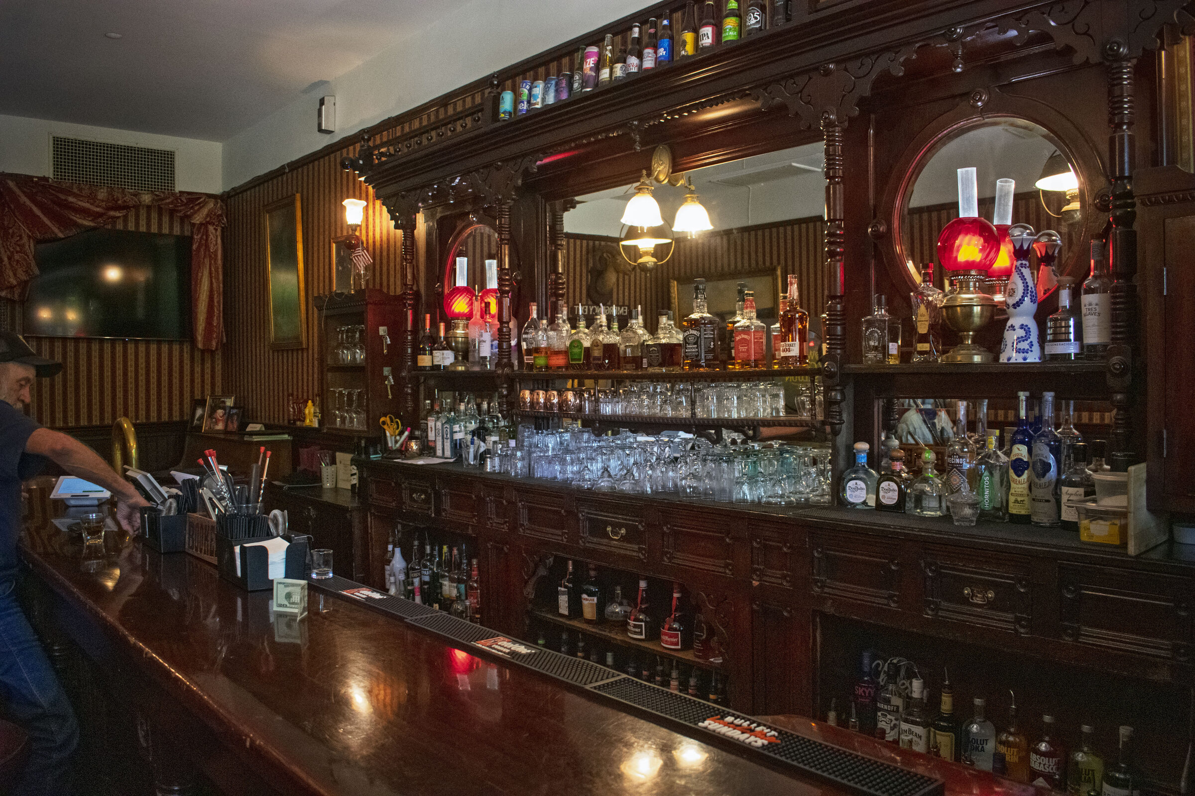 A carved wooden back bar with mirrors, lamps and bottles in a Columbia hotel saloon