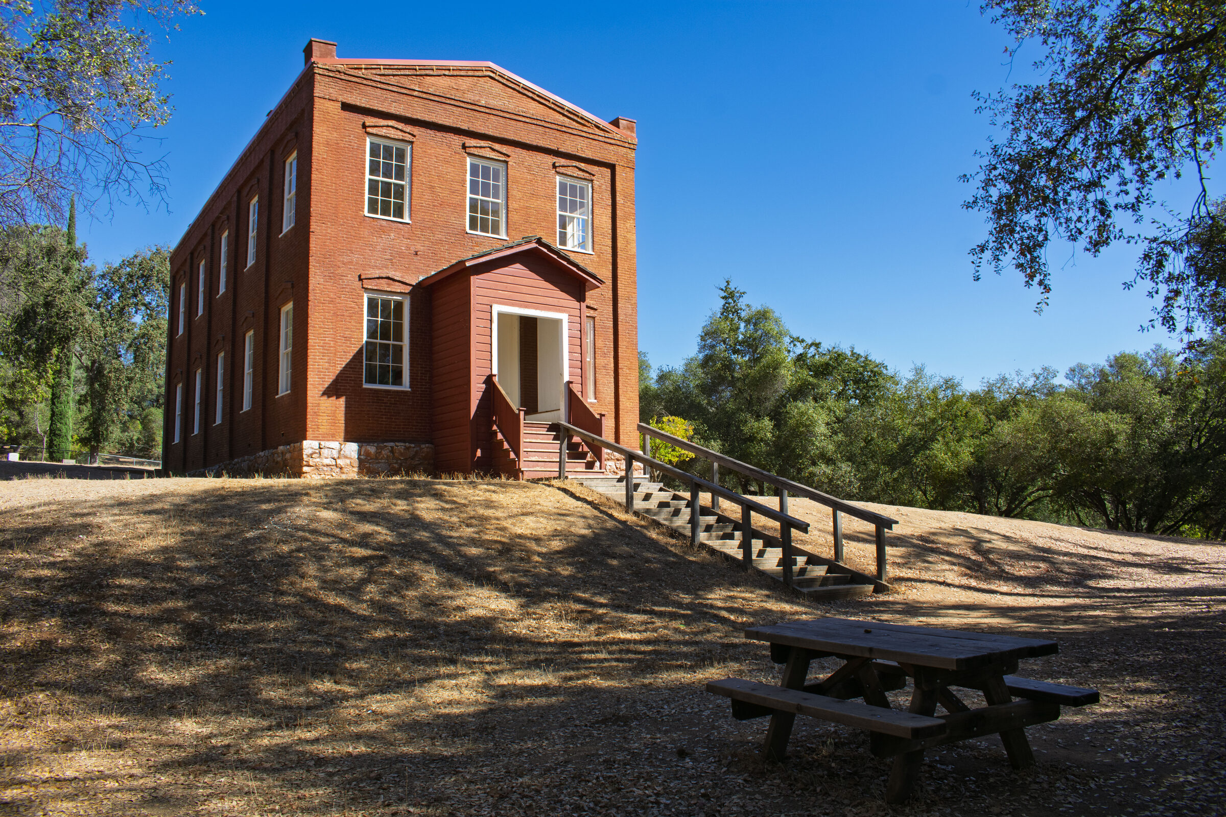 The two-story red brick Columbia Schoolhouse on its hill under a blue sky