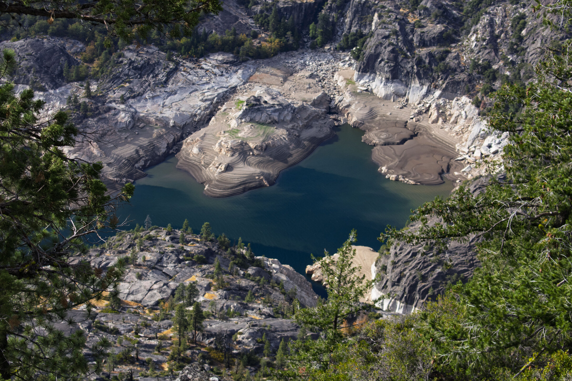 Donnell Reservoir in a granite basin seen through pines from Donnell Vista on Highway 108