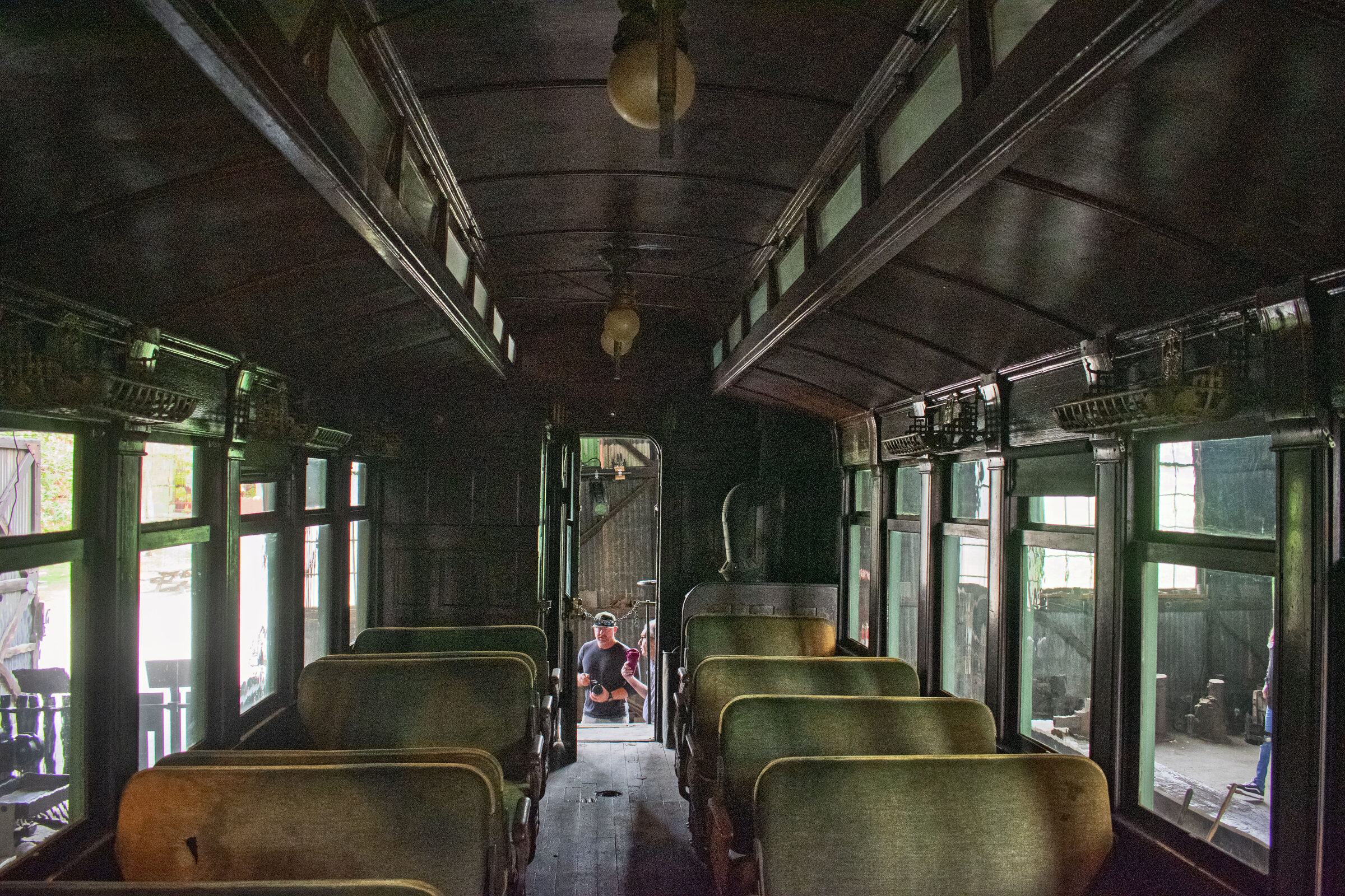 Rows of green upholstered seats inside a wooden Sierra Railway passenger coach