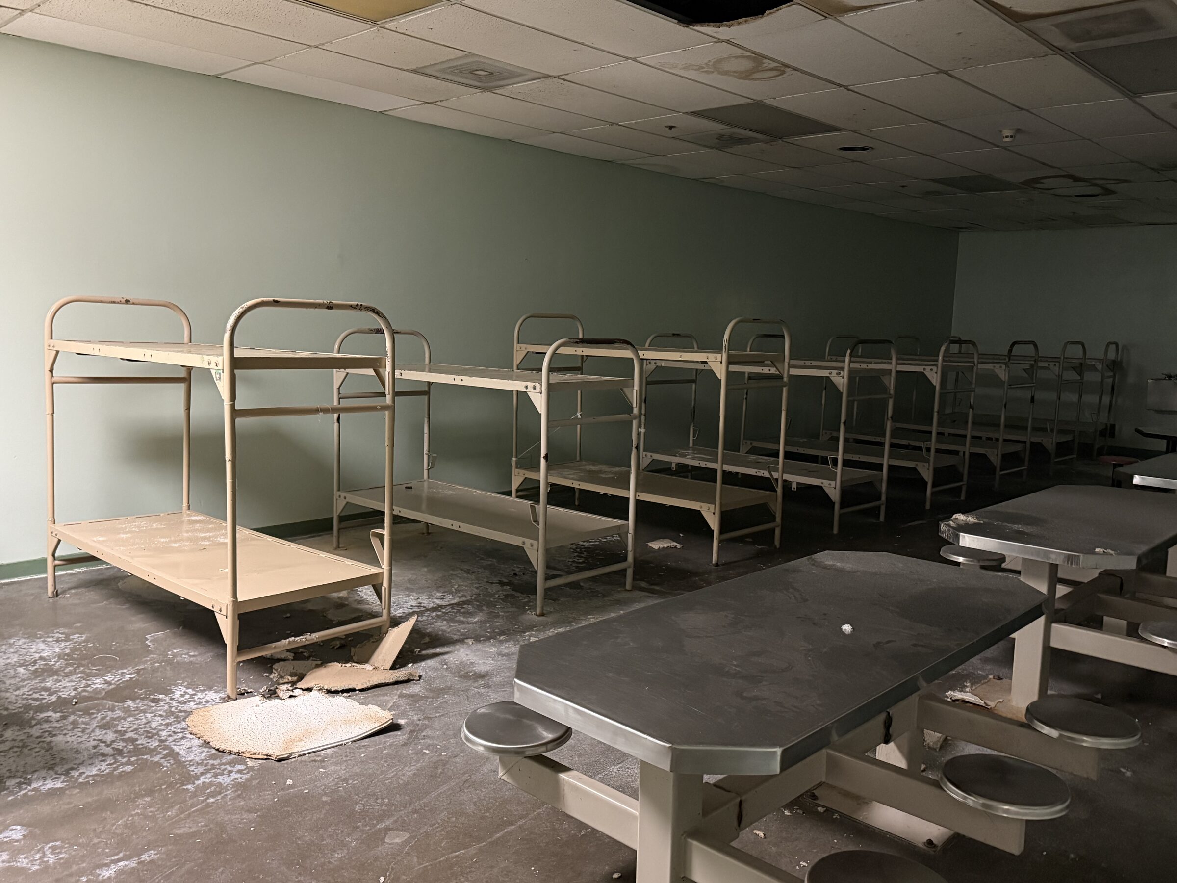 Empty bunk beds and steel tables in a dormitory at the vacant Tuolumne County Jail