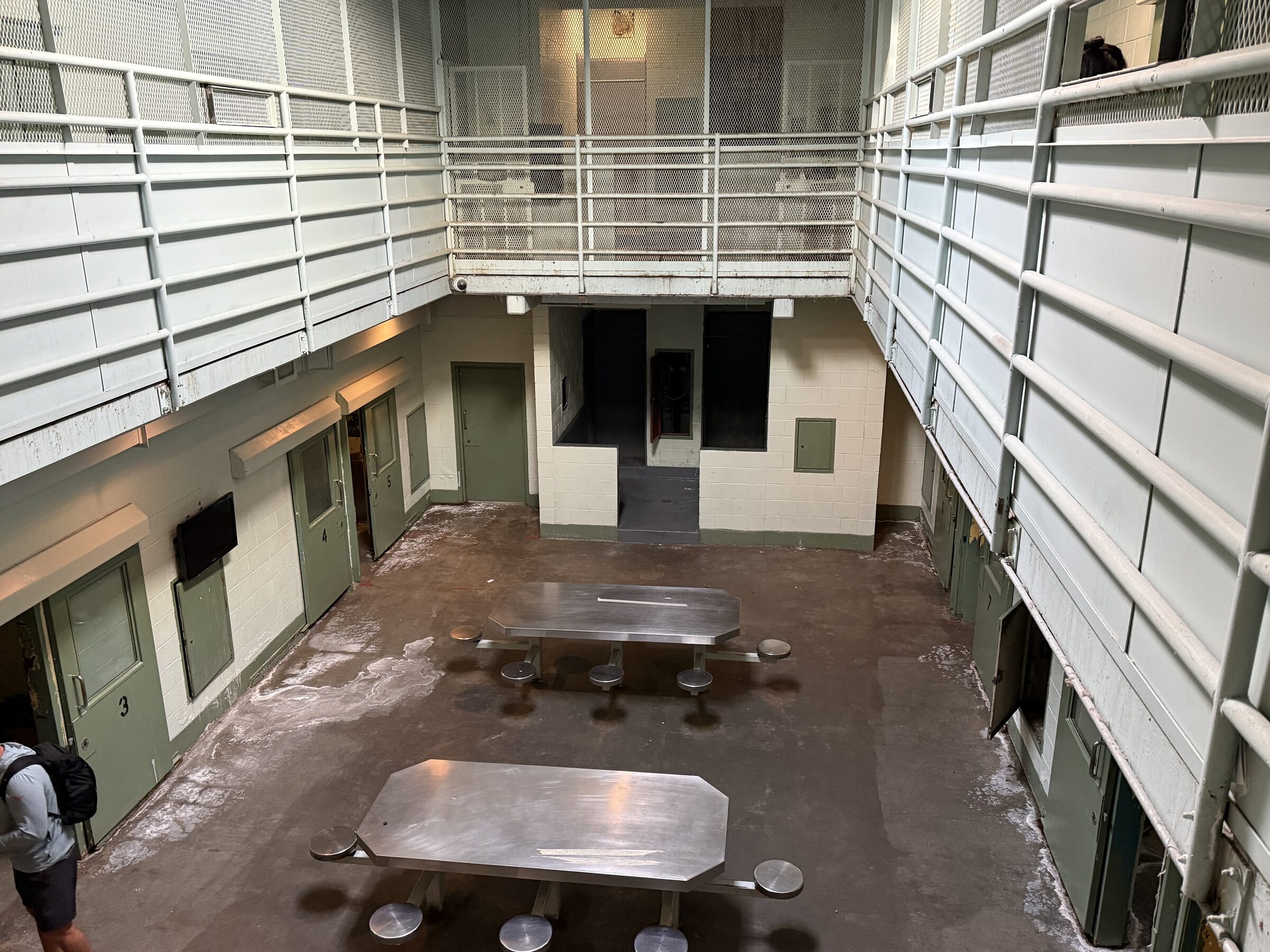Two-tier housing unit inside the vacant Tuolumne County Jail in Sonora, with steel tables on the dayroom floor